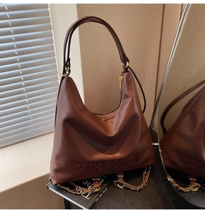Dettaglio borsa hobo in pelle marrone con lettere a rilievo e catena dorata