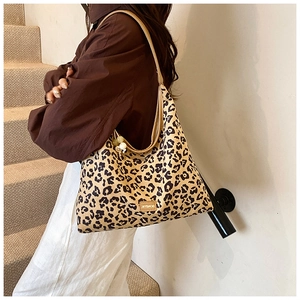 Detail of leopard print tote bag with brown leather strap and side pearl decoration