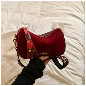 Detail of burgundy suede crescent bag featuring a folk-style embroidered wide strap