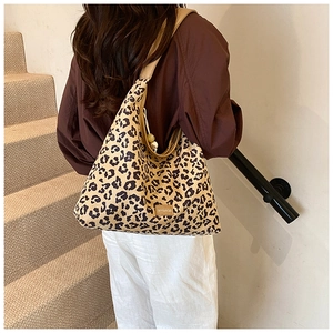 Detail of leopard print tote bag with wide shoulder strap shown on model outdoors
