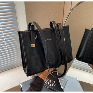 Detailed view of woven texture and metal ring buckle on a black leather tote bag