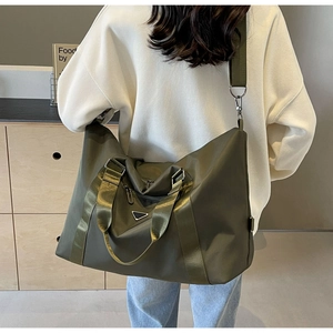 Olive green nylon travel bag shown on shoulder, highlighting size and carry style