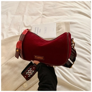 Detail of burgundy crescent bag with fashion logo and geometric woven shoulder strap