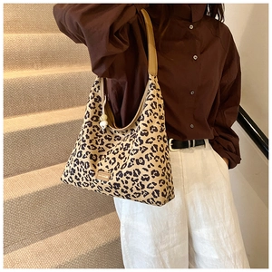 Detail of leopard print tote bag featuring pearl charm and durable canvas texture