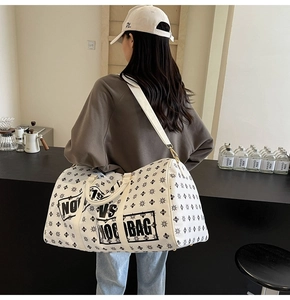 Vista dettagliata della borsa da viaggio crema con monogramma e tracolla in un caffè