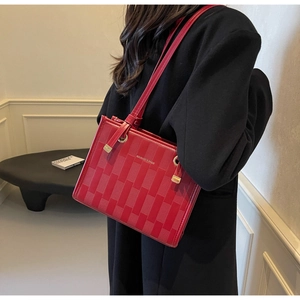 Detail of red woven texture shoulder bag worn by model with minimalist modern background