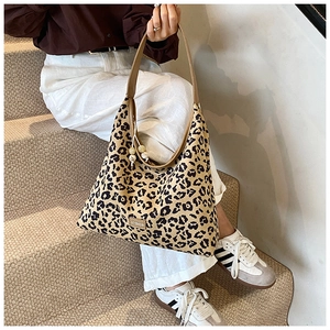 Detail of leopard print tote bag with wooden bead charm and brown leather straps