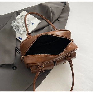 Detail of retro brown leather handbag with double front pockets and metal zipper closure