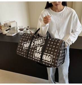 Dettaglio della borsa da viaggio grande monogramma con testo bianco tenuta da modella