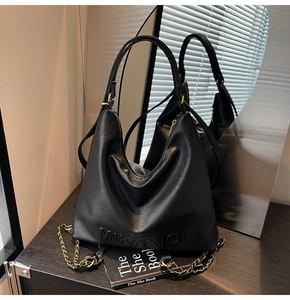 Dettaglio macro della borsa tote in pelle nera con catena metallica e logo impresso