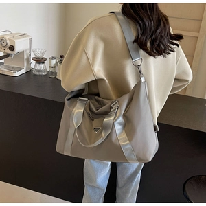 Detailed view of the large capacity khaki nylon travel bag with a silver triangular logo