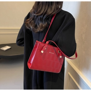 Detail of red tote bag with woven texture and long shoulder strap on black coat