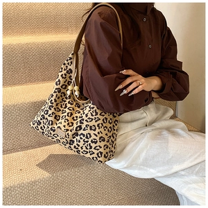 Detail of hobo bag featuring leopard print, pearl charm, and metallic brand label