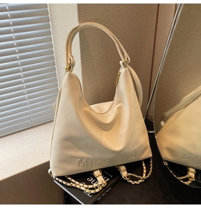 Dettaglio borsa hobo beige con logo MIKAXIQI e catena metallica decorativa