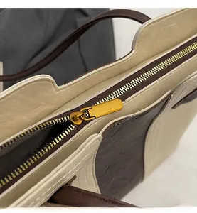 Detailed view of the smooth golden metal zipper and textured off-white tote bag