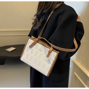 Detail of white woven texture and brown trim on the commuter shoulder tote bag