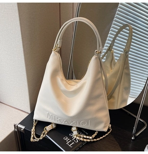 Dettaglio della borsa tote bianco crema con logo goffrato e tracolla in pelle e catena