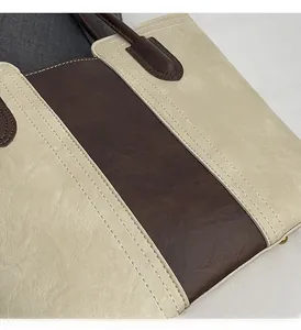 Detailed macro view of two-tone beige and brown tote bag with white stitching texture