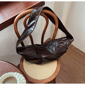Detail of dark brown glossy leather hobo bag with pleats and crescent moon shape
