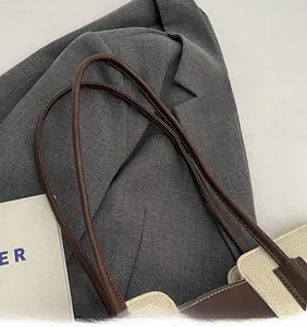 Detailed close-up of smooth brown leather straps and stitching on a bicolor tote bag