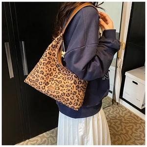 Close-up of leopard print shoulder bag with brown leather strap and brand badge details