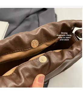 Macro detail of the dual magnetic closure on a brown vintage drawstring bucket bag