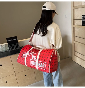 Dettaglio della borsa da viaggio rossa grande con monogramma e tracolla su una modella