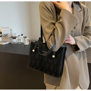 Fashionable black woven tote bag shown on model with chic cafe background
