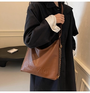 Dettaglio della borsa tote in pelle marrone con logo MIKAXIQI e tracolla a catena