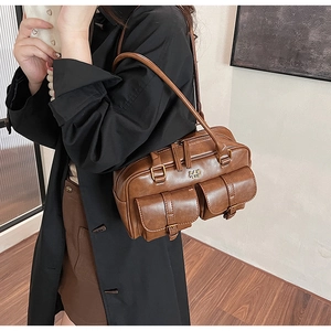 Detail of vintage brown barrel bag featuring two front buckled pockets and metallic logo