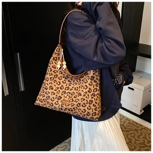 Detail of leopard print tote bag with wooden bead charm and logo plaque on shoulder