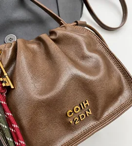 Close-up of brown textured leather bucket bag with golden logo and key charm