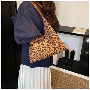 Detailed view of leopard print canvas tote bag with brown leather shoulder straps