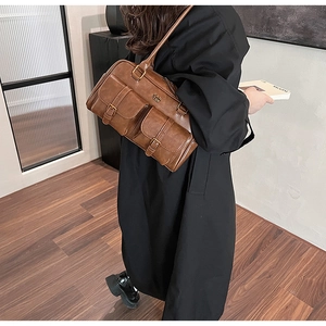 Detail of a brown vintage leather shoulder bag with two front metal buckle pockets