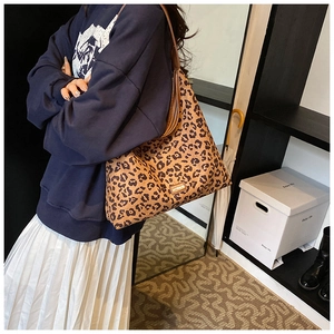 Detail of leopard print tote bag featuring a leather logo tag and brown shoulder straps