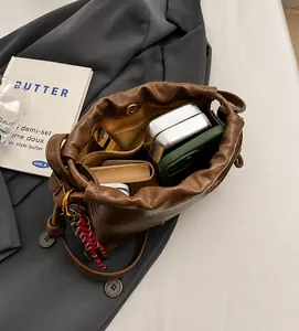 Top view of brown pleated crossbody bag interior showing phone, wallet and cosmetics