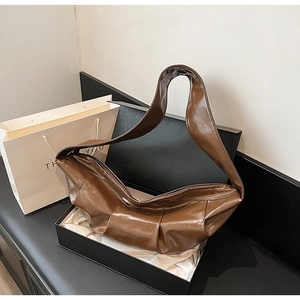 Brown high-gloss pleated dumpling bag with wide strap displayed in a premium gift box