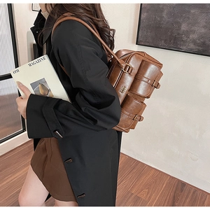 Detail view of a brown vintage leather shoulder bag with pockets shown on a model