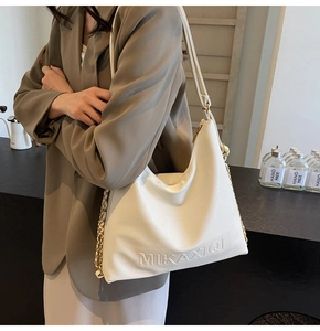 Dettaglio della borsa tote color crema in PU con logo goffrato e tracolla a catena