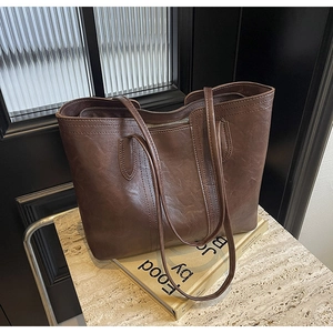 Detailed view of dark brown tote bag on marble stand with textured leather and zipper