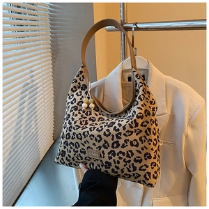 Detailed leopard print tote bag with brown leather strap and decorative beaded pendant charm