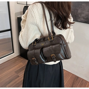 Detail view of a vintage dark brown shoulder bag with dual front flap pockets and buckles