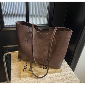 Detailed view of brown vintage tote bag with PU leather texture on a stone surface