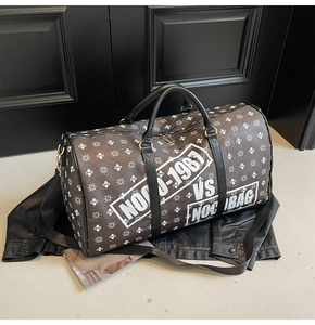 Dettaglio di una borsa da viaggio cilindrica con motivi geometrici e scritte bianche
