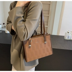 Macro view of dark khaki tote bag showing geometric embossed pattern and gold buckle