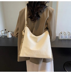 Dettaglio borsa tote bianca con logo a rilievo e tracolla a catena in metallo lucido