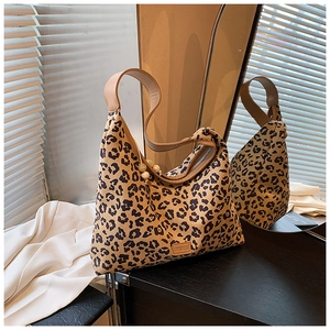 Detailed view of leopard print tote bag with brown shoulder strap and brand label