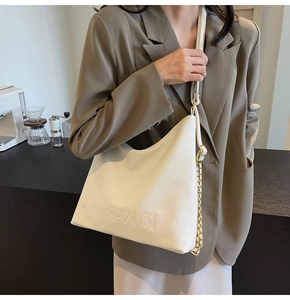 Dettaglio della borsa tote bianco sporco con logo a rilievo e tracolla a catena metallica