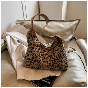Close-up of leopard print canvas bag featuring a brown strap and bead charm detail