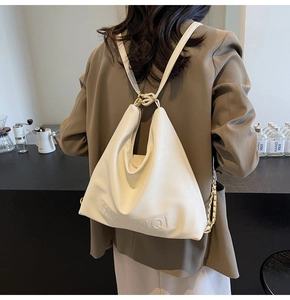 Dettaglio della borsa tote multifunzionale in pelle crema indossata come zainetto